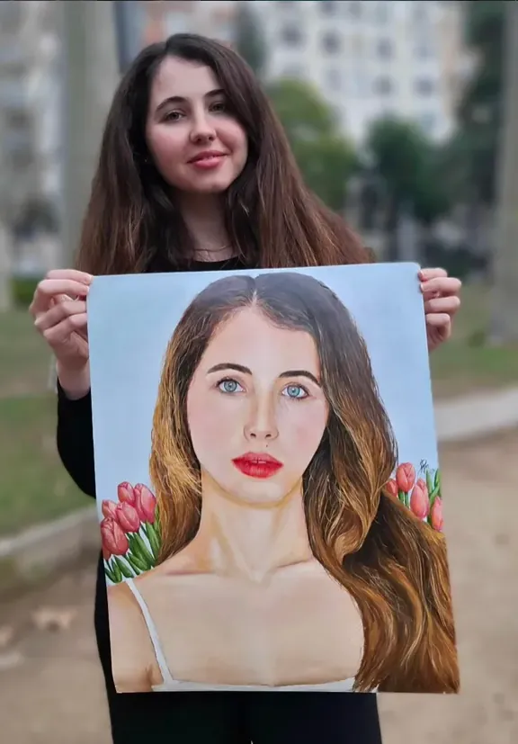 Una mujer sostiene su retrato pintado por Ariel Perez